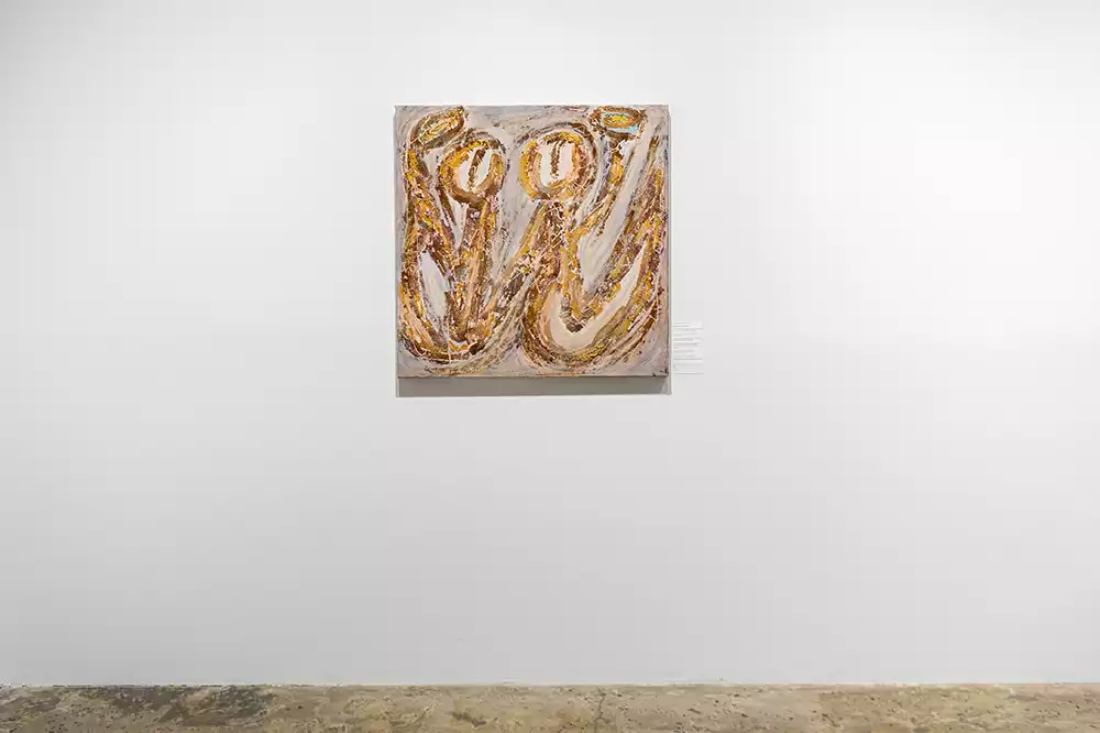 Kasia Muzyka's painting "I and Ja" on a white gallery wall, featuring two prominent, golden, looping figures against a textured, neutral background