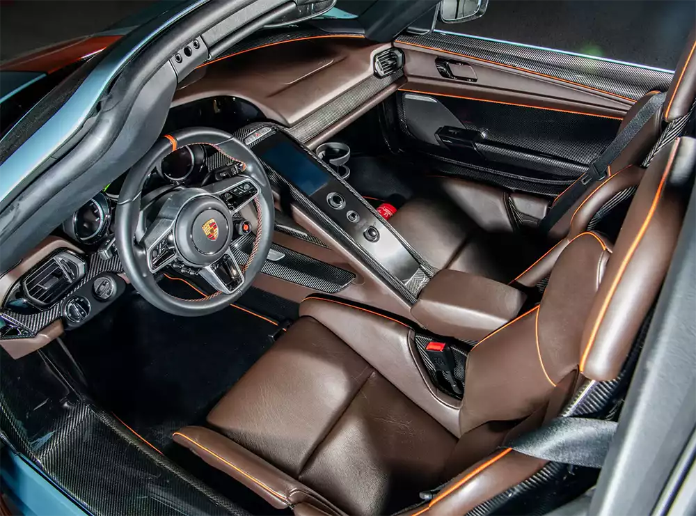 Interior cockpit of the Porsche 918 Spyder featuring Mocha Brown leather with Arancia Mira orange piping
