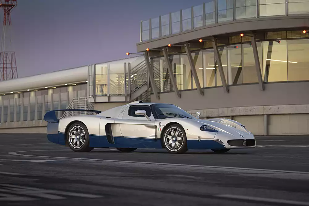 Side profile of the white and blue Maserati MC12 Stradale on an airfield tarmac