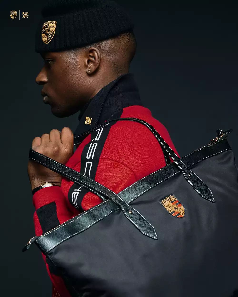 Close-up of the Aimé Leon Dore × Porsche FW25 black nylon travel bag with leather trim and embroidered Porsche crest