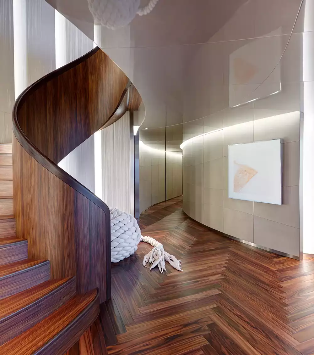 The striking dark wood spiral staircase connecting the decks of the Savannah superyacht