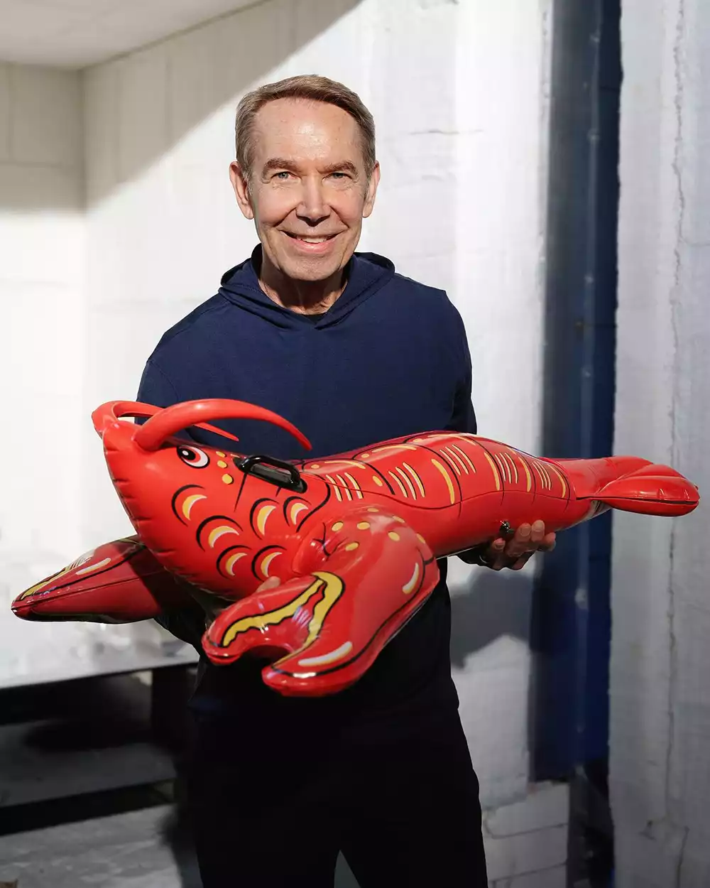 Artist Jeff Koons holding the red porcelain lobster collector's edition