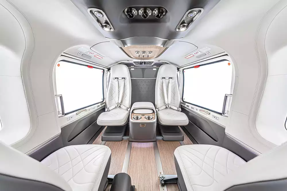 Luxurious interior of the Airbus ACH145 Mercedes-Benz Edition helicopter, featuring light leather seats, wooden flooring, and spacious cabin design