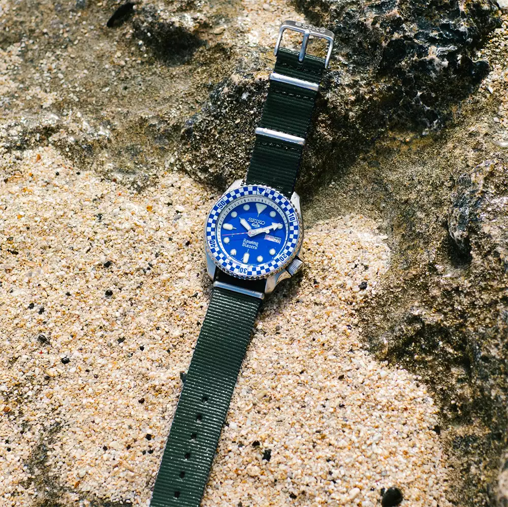 Seiko x Rowing Blazers Rally Diver blue dial watch with green nylon strap on stone surface