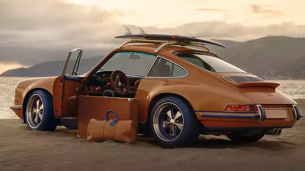 Orange Porsche 911 Reimagined by Singer Classic with Louis Vuitton luggage on the door